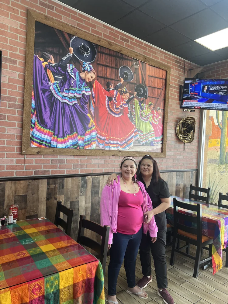 Two caregivers posing together during a community outing at a local restaurant