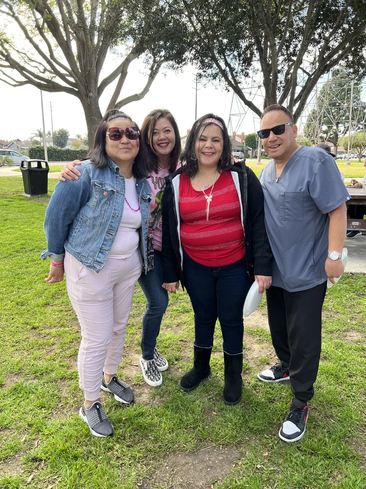 Group of four people smiling together at an outdoor community gathering