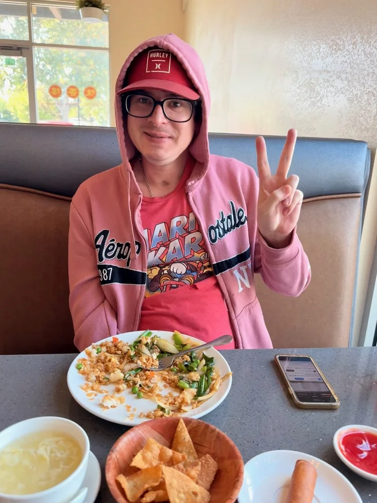 Resident enjoying a meal in community dining area making peace sign gesture