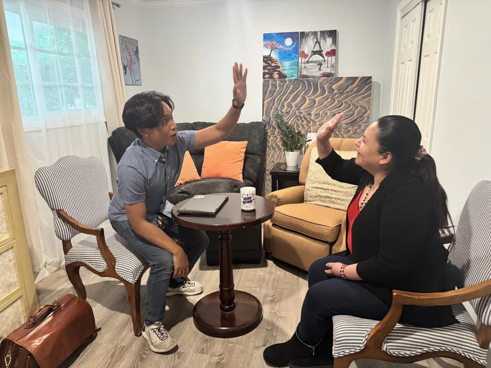 Caregiver and resident engaged in therapeutic conversation in comfortable living room