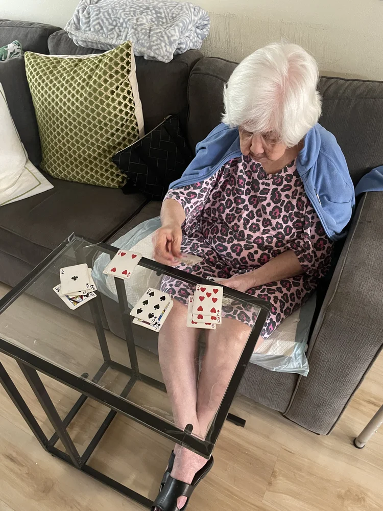 Senior resident playing cards independently in comfortable living room setting